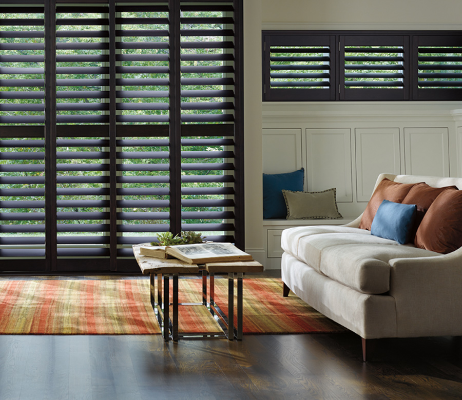 living room with orange rug and hunter douglas black heritance hardwood shutters Cleveland