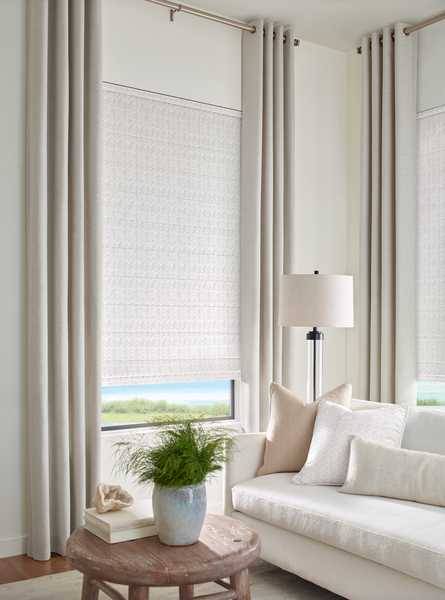neutral design in living room with drapery on tall windows and fabric shades