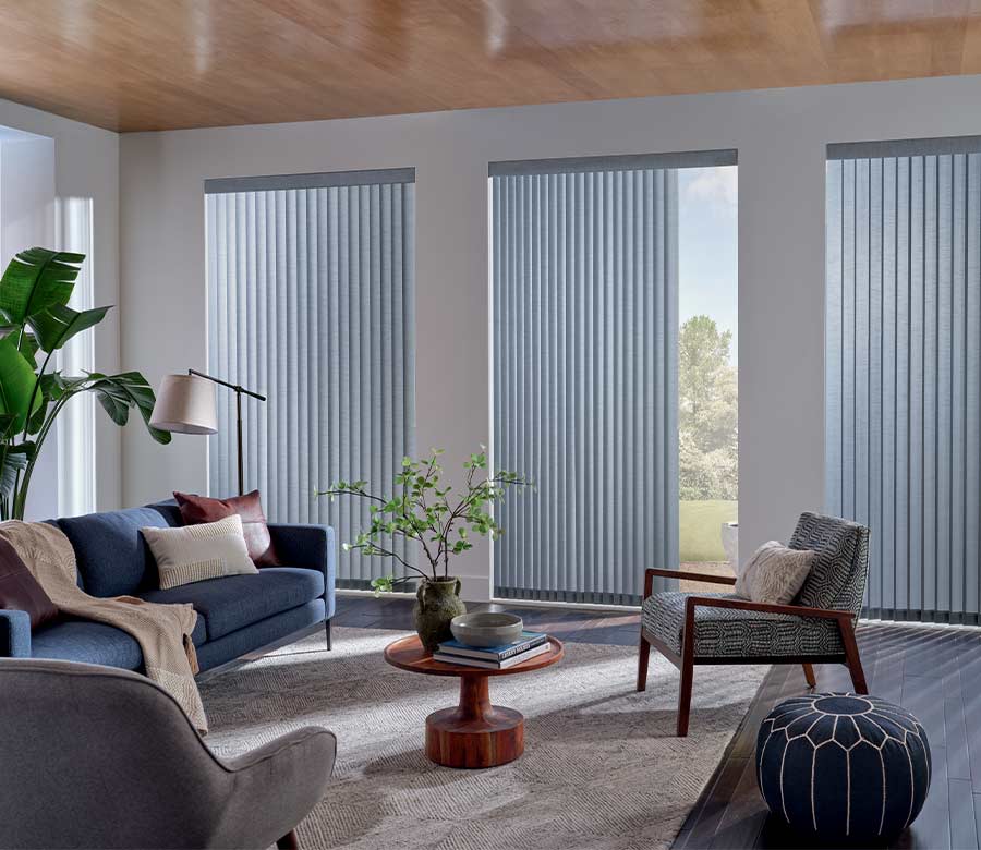 blue couch in living space next to vertical shades in soft blue fabric