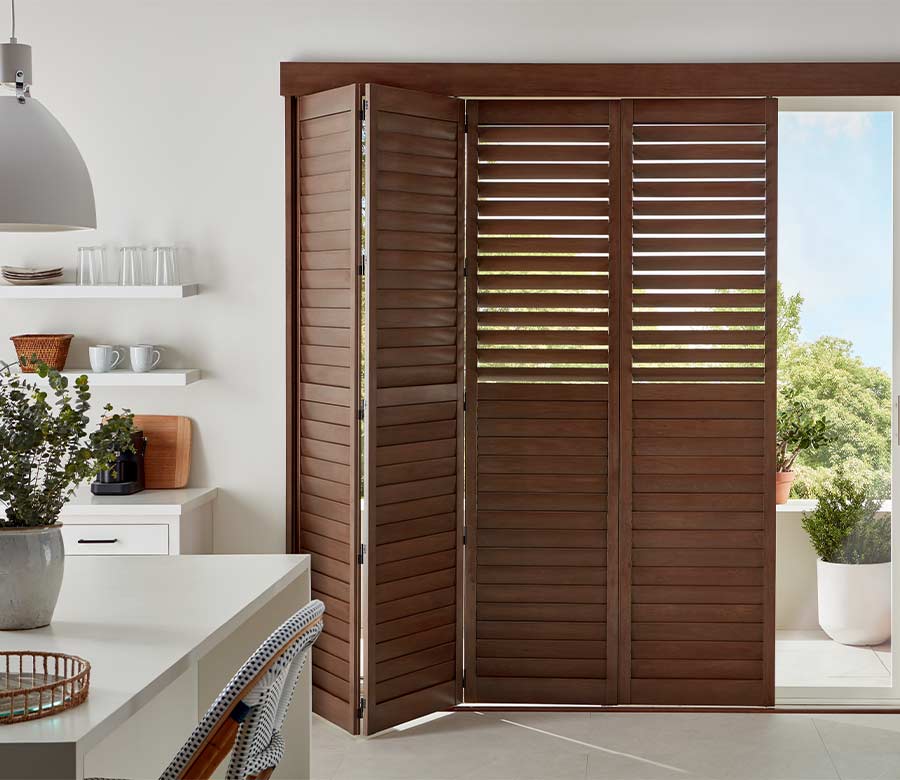 bifold wood grain shutters in dark mahogany in white kitchen