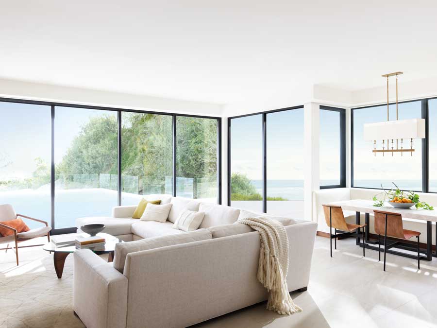 Floor to ceiling black trim windows in a living room overlooking a scenic backyard