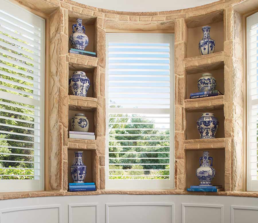 white plantation shutters on bay window with stone built ins