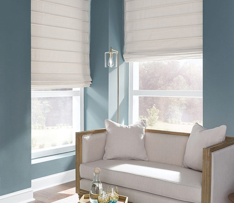 cream fabric shades in corner window blue walls and loveseat