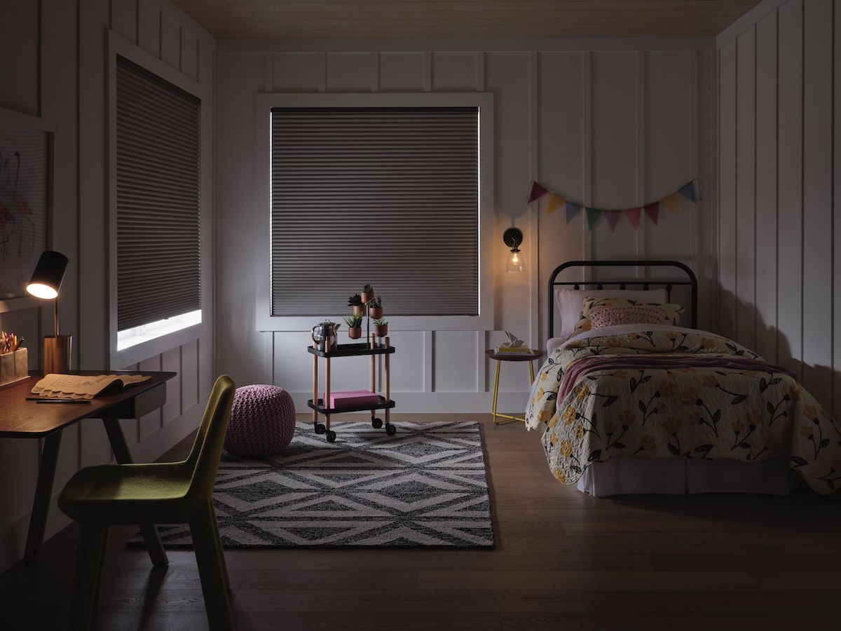 Applause® Honeycomb Shades in a child's bedroom. They are covering two windows on the left and back window with a twin bed to the right.