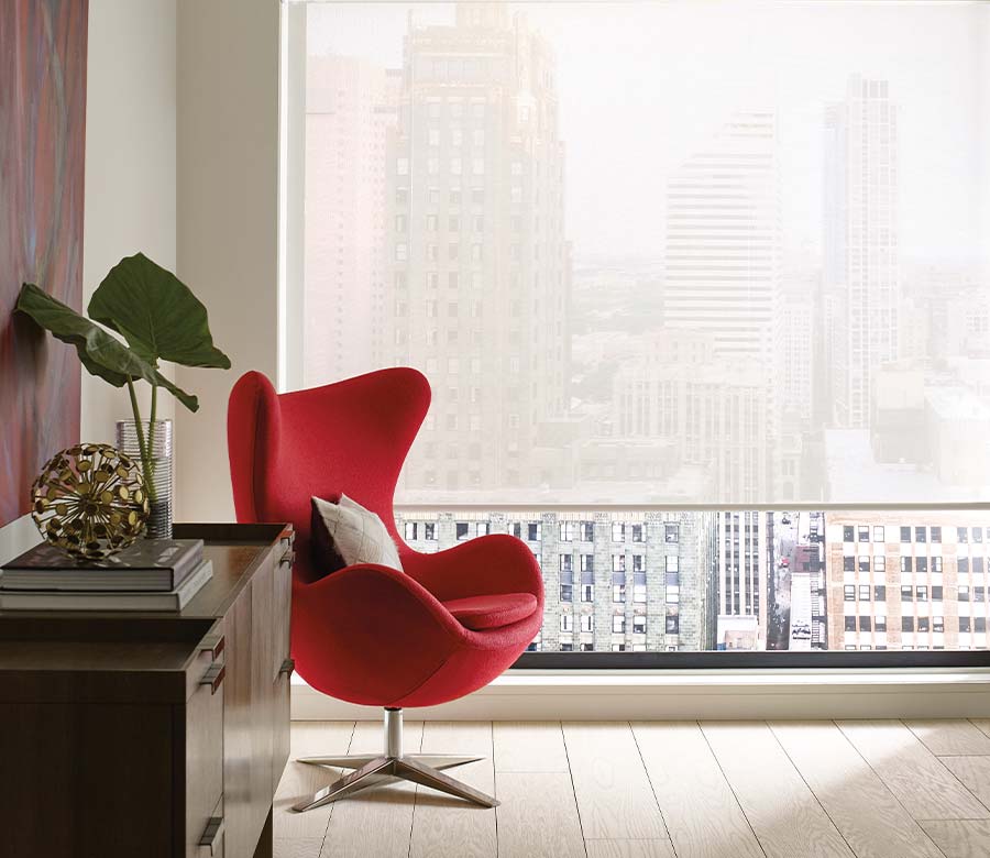modern red barrel chair in front of large square window with shade half way down
