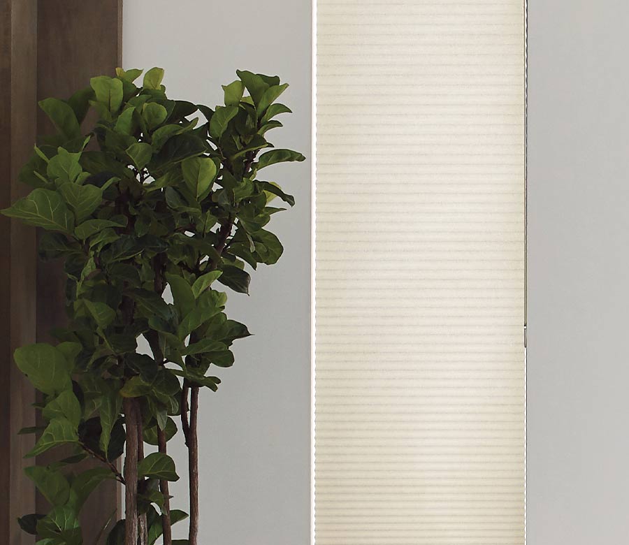 large skinny window covered by a tan window shade for room darkening and energy efficiency
