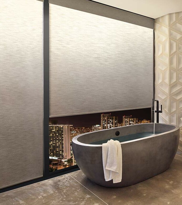 a modern bathroom with a tub next to large windows covered by illuminated privacy shades