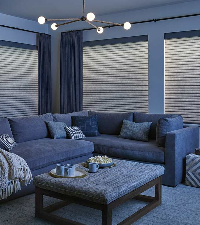 in-home media room with drapery side panels and a light illuminating window shade