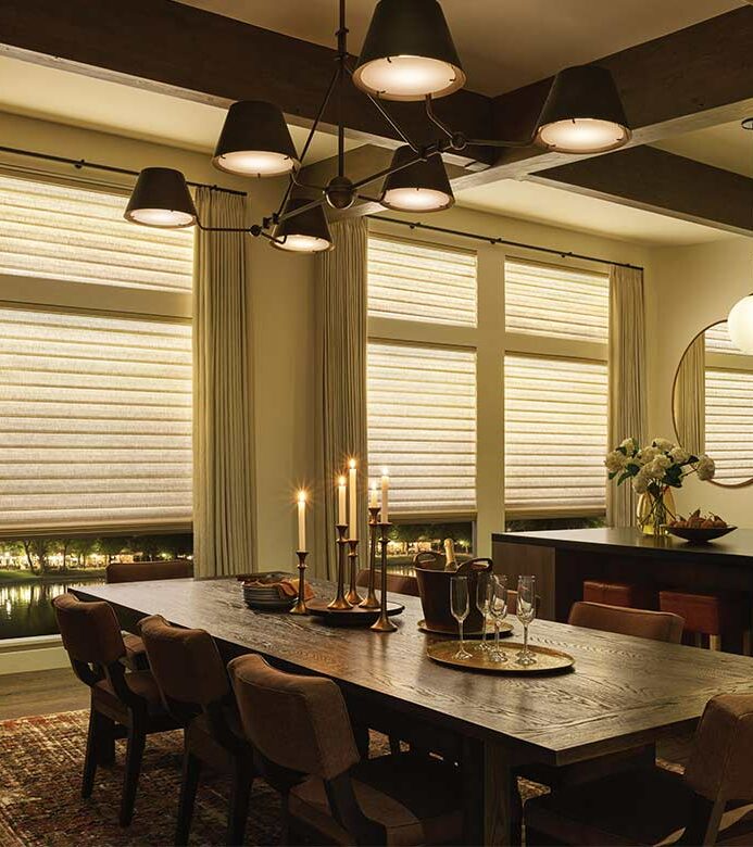 a cozy dining room set for dinner and side draperies layered over aura shades