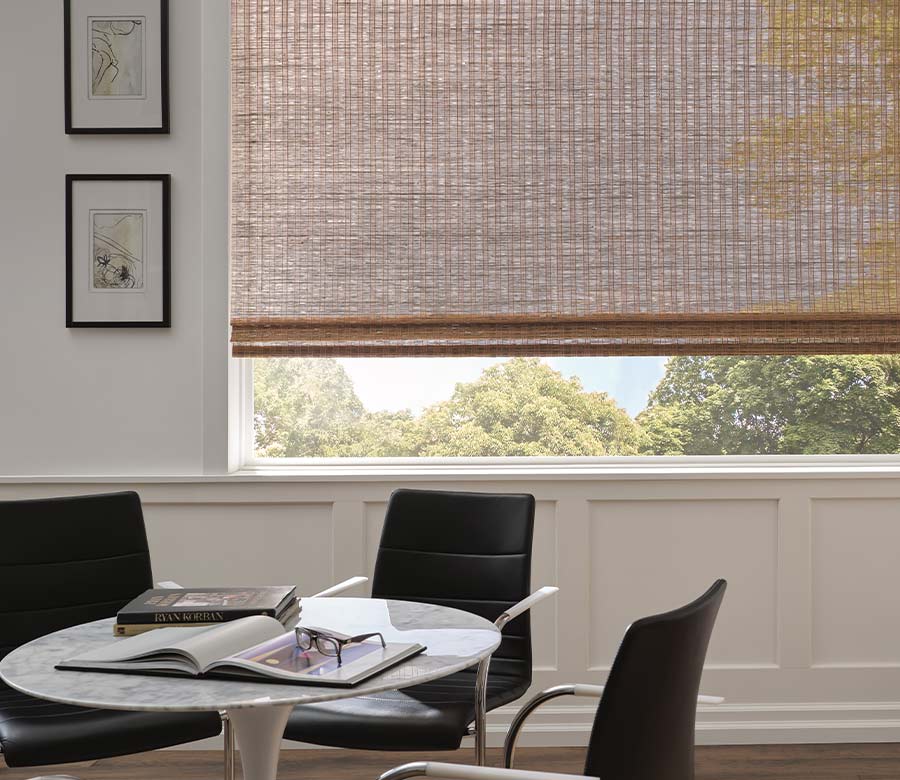 home office space with a large window shade behind the working space