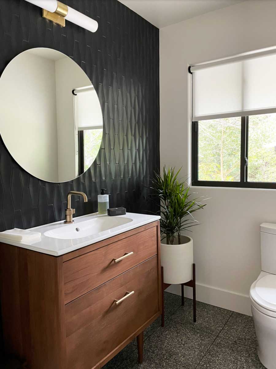 small bathroom with natural wood vanity and black accent wall