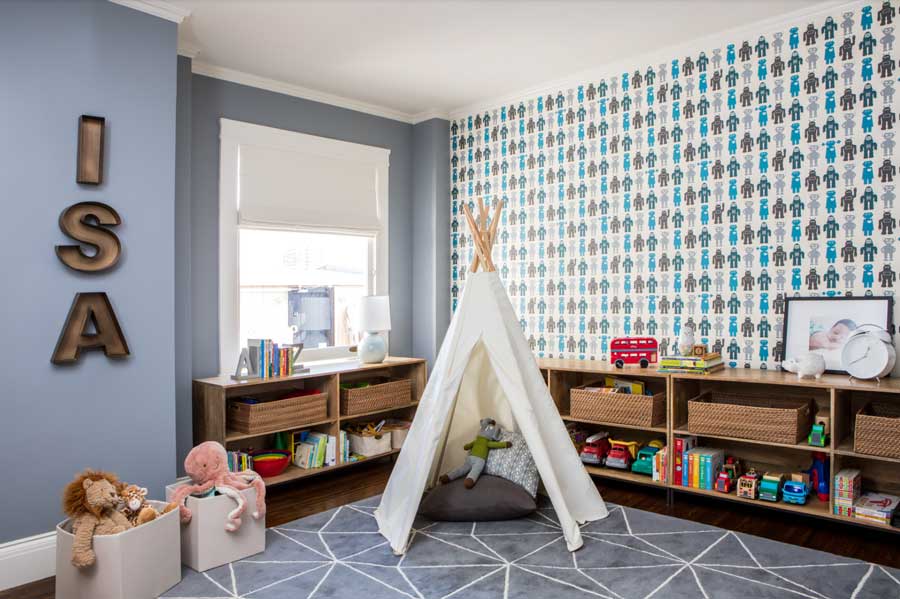 A kids playroom with built in bookshelves, a white teepee and baskets of toys
