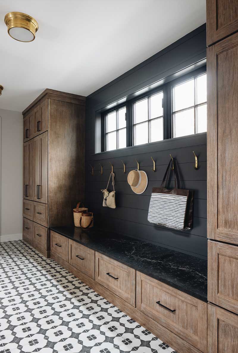 A neutral tone mudroom with sandy brown built ins, hooks with purses and hats and a tile floor