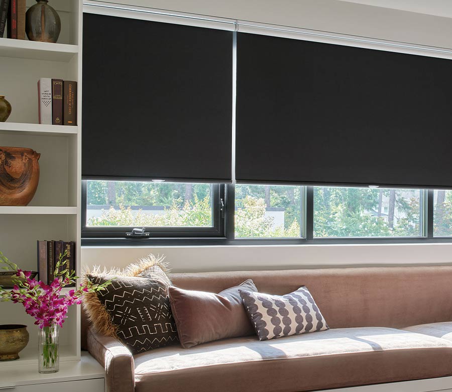 black shades on window above reading bench flanked by white cabinets with home decor