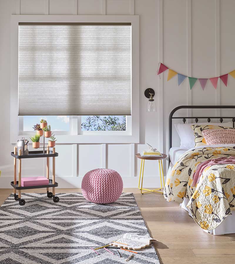 child's bedroom with beige honeycomb shades with cordless operation for child safe blinds, pink and yellow room decor