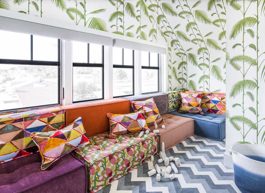 colorful interiors fill this home playroom with wallpaper and couch cushions