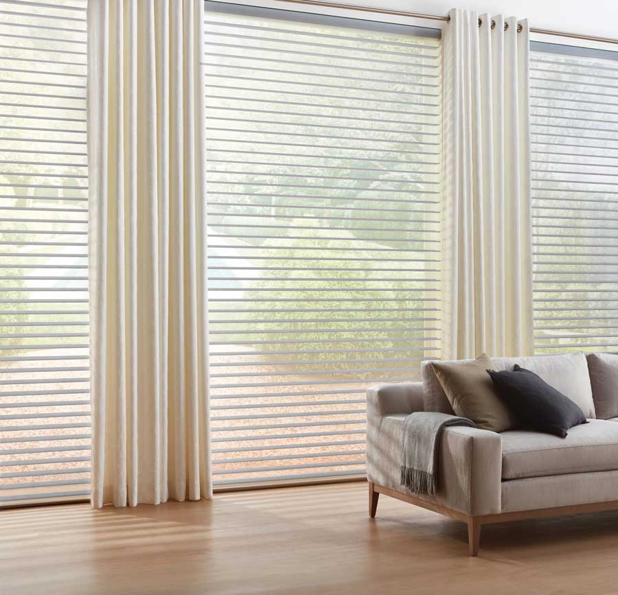 large windows in living area neutral and with sheer shades and drapes